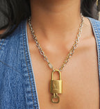 Gold padlock necklace worn by a person with a denim jacket