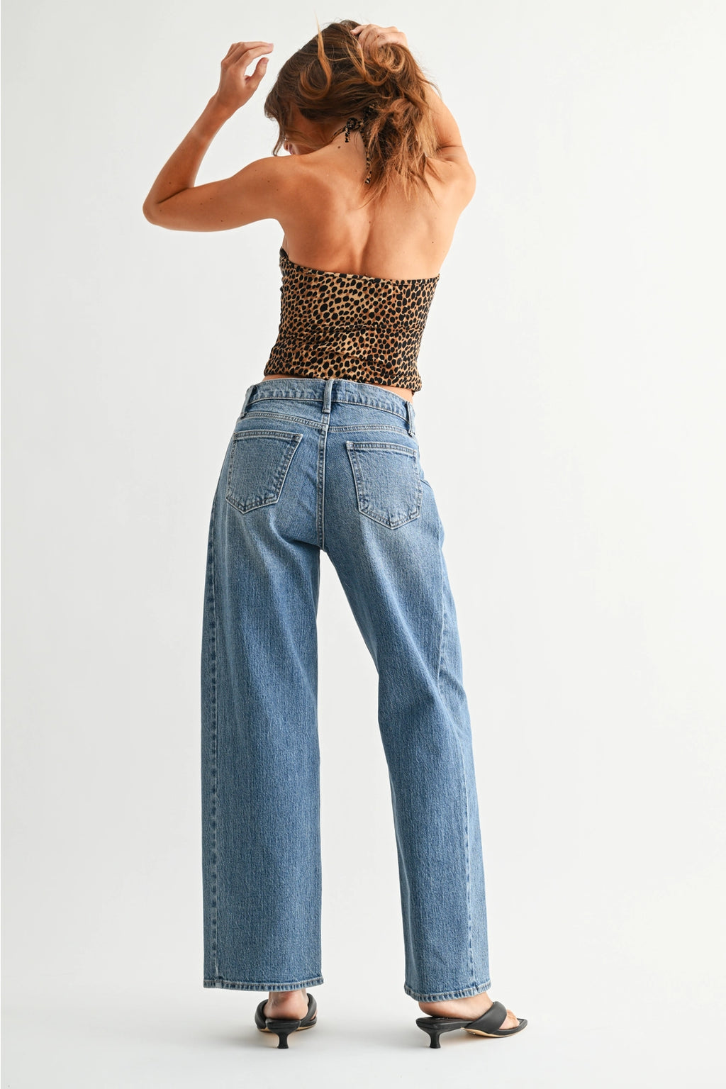 Woman wearing a leopard print top and blue jeans on a white background
