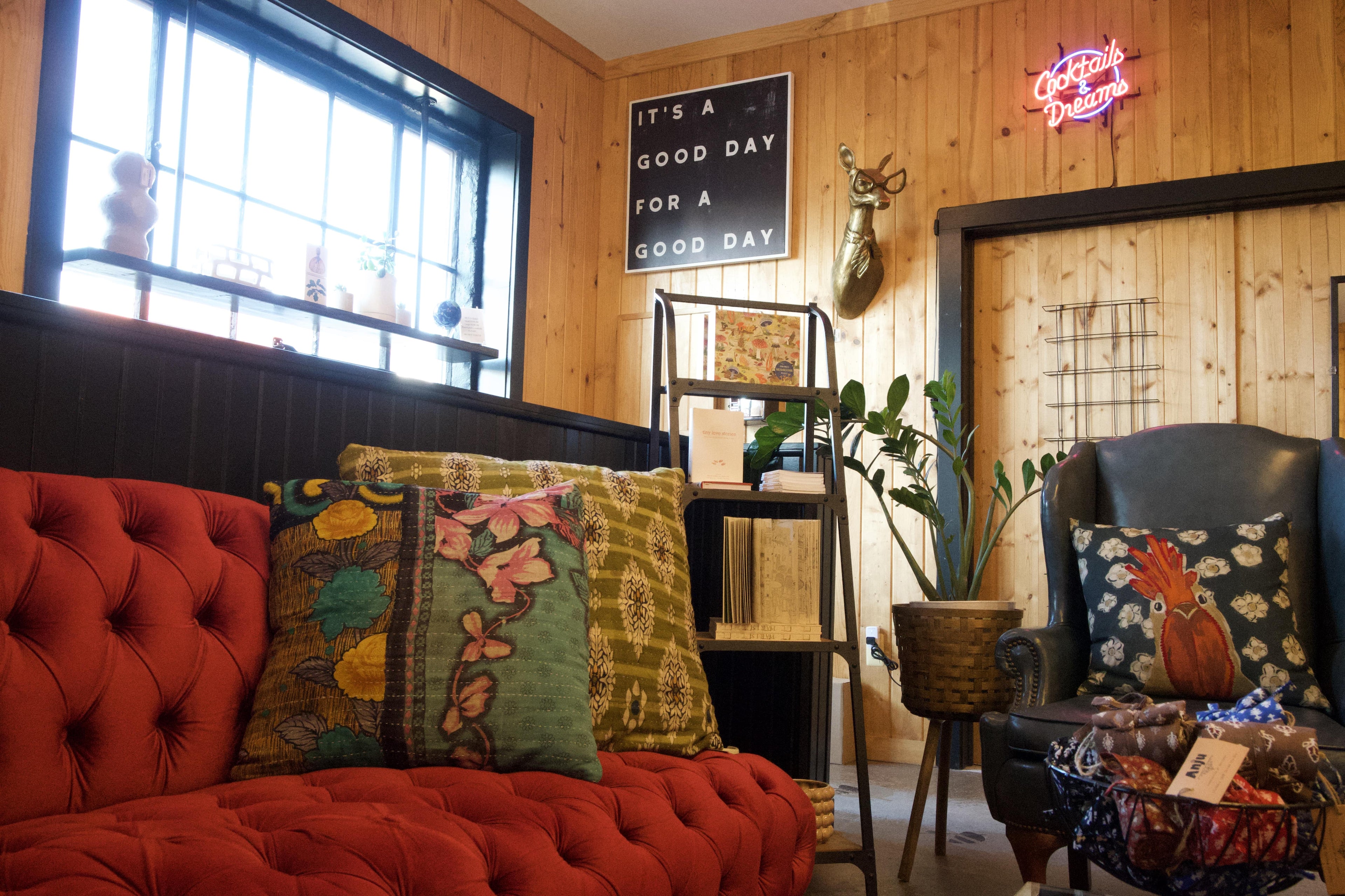 Living room with red sofa, decorative pillows, and a neon sign.