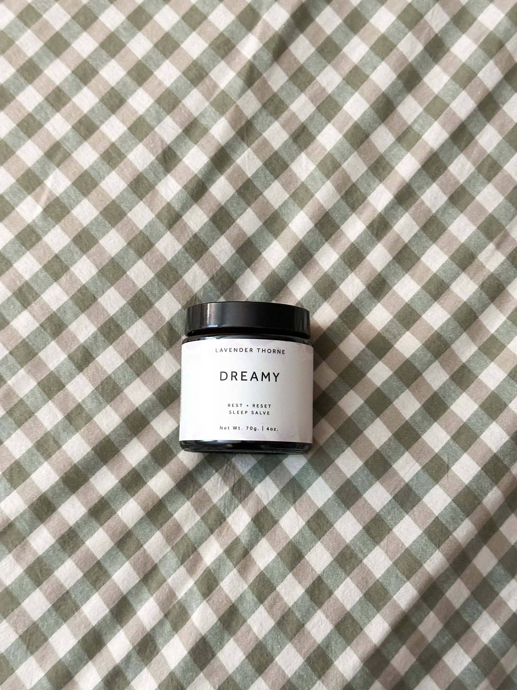 Small jar labeled 'Dreamy' on a green and white checkered fabric background