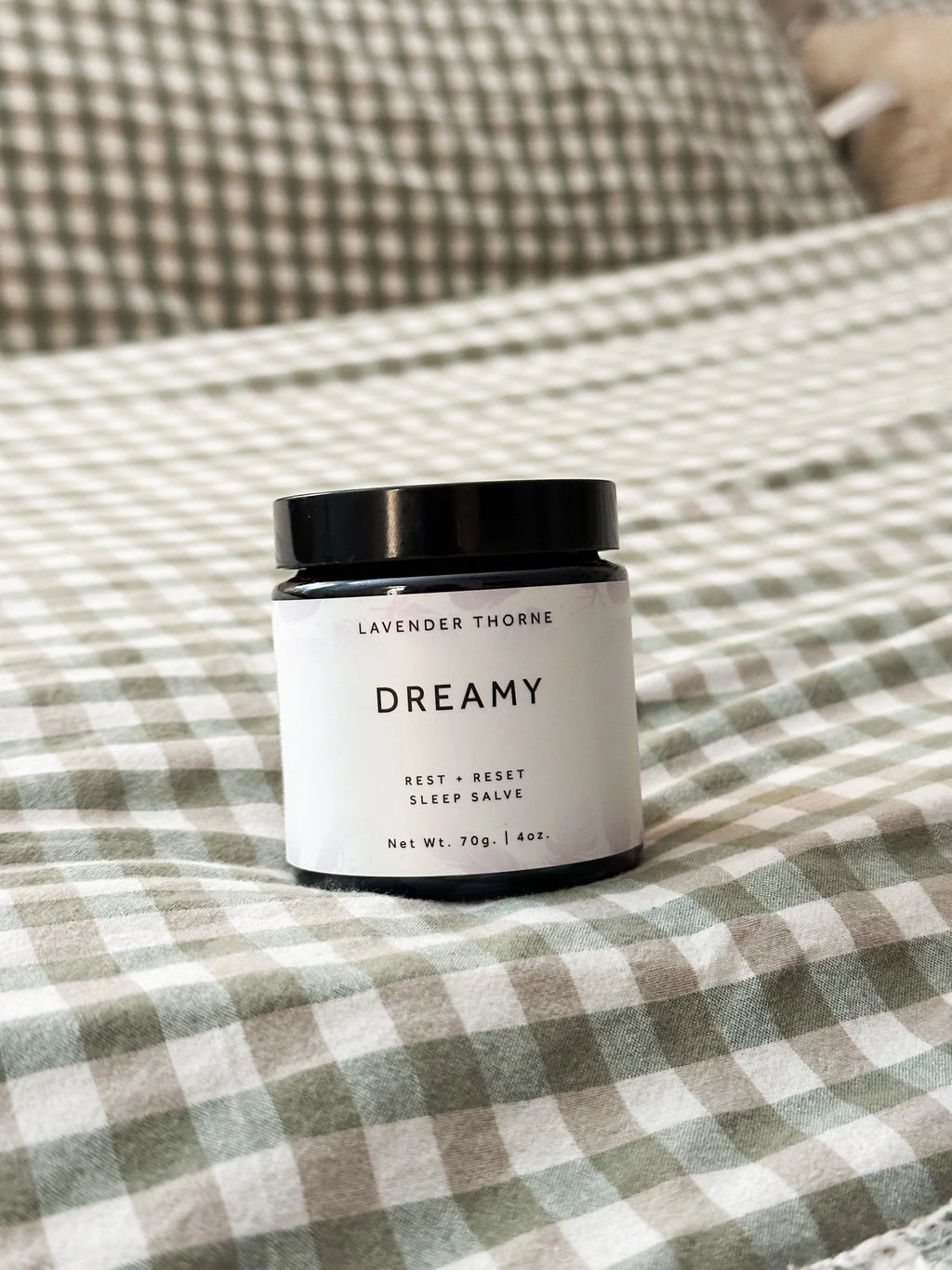 Candle labeled 'Dreamy' on a checkered fabric surface