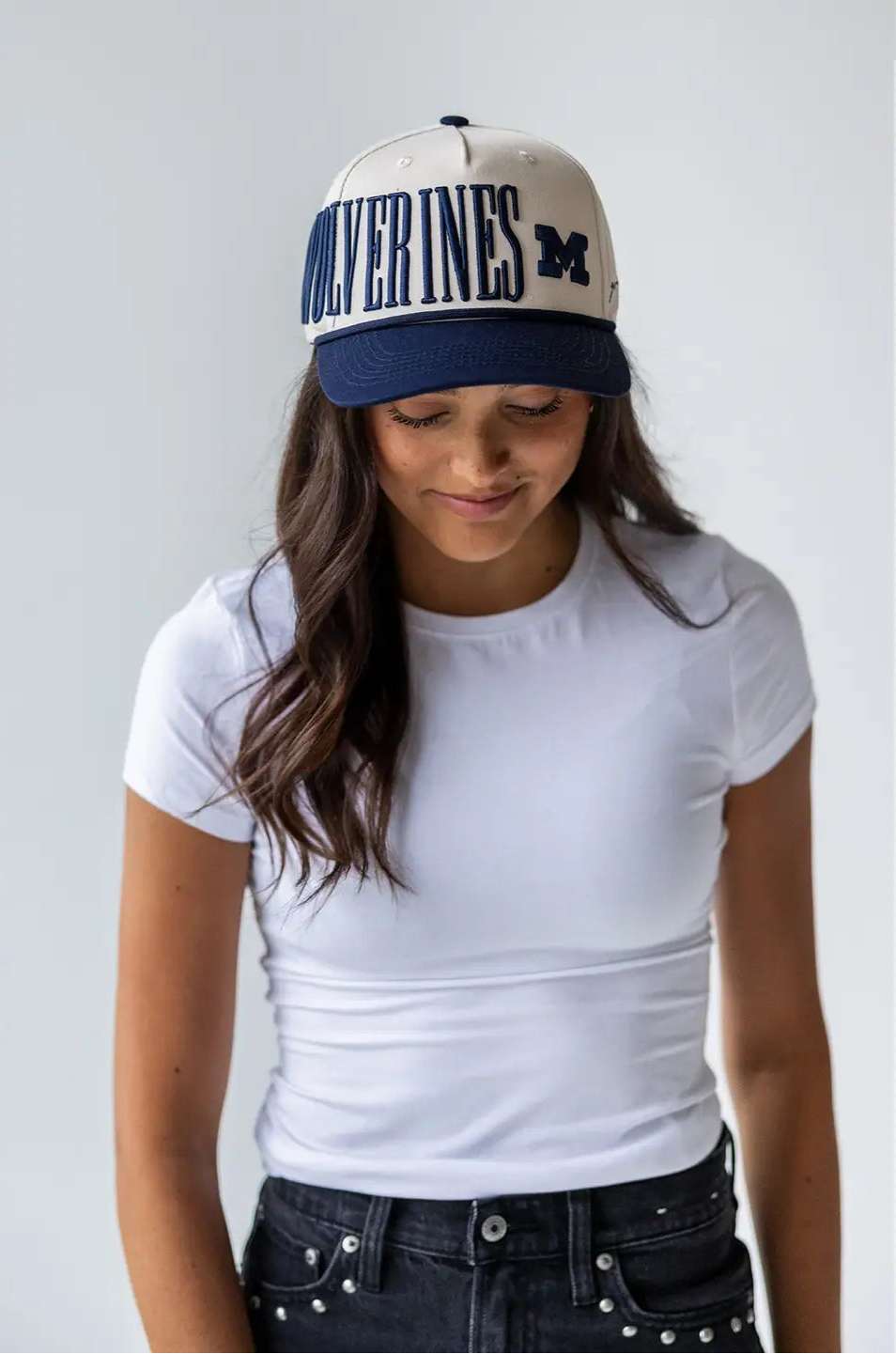 Person wearing a cap with 'Wolverines' text on a plain background