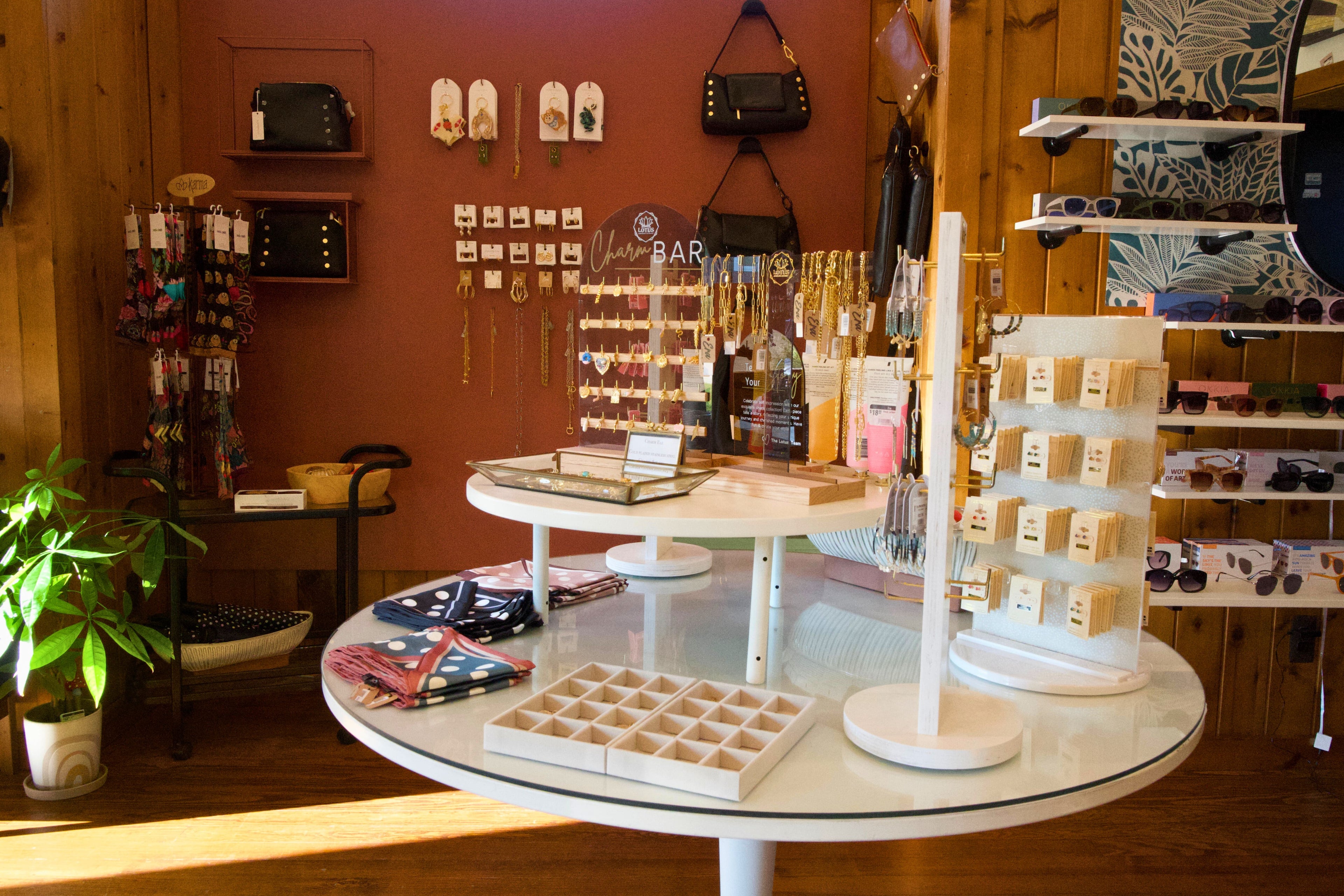 Display of jewelry and accessories in a store with wooden walls and a round glass table.